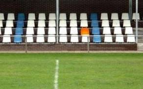 Oranje stoel op tribune met witte en blauwe stoelen