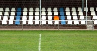 Oranje stoel op tribune met witte en blauwe stoelen