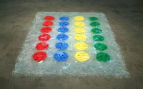 Op de grond ligt een Twisterspel met rode, blauwe, gele en groene stippen, gemaakt van glasscherven.