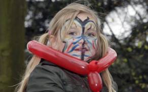Geschminkt meisje met rode ballon om haar nek, buiten