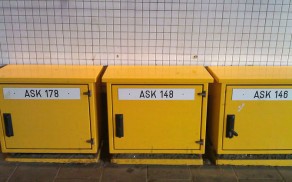 Gele kastjes met tekst ASK178, ASK148, ASK146 voor een witte muur